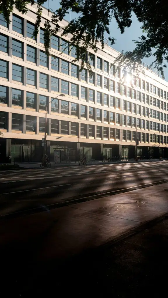Modern office building facade reflecting sunlight on an urban street.